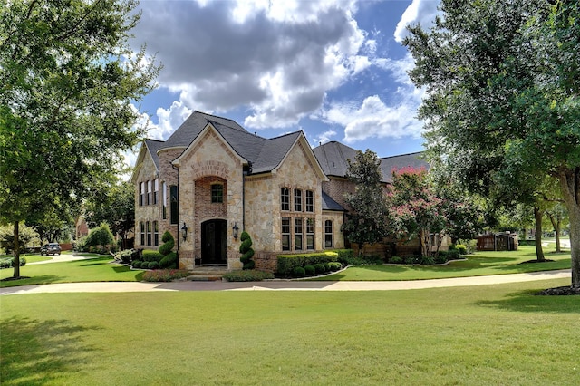 french country inspired facade featuring stone siding and a front lawn