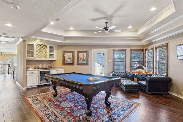 recreation room featuring a bar, a tray ceiling, beverage cooler, and dark wood-style flooring