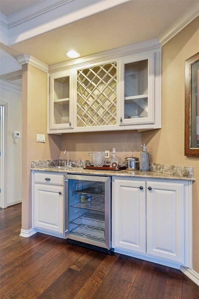 bar with wet bar, crown molding, beverage cooler, and dark wood finished floors