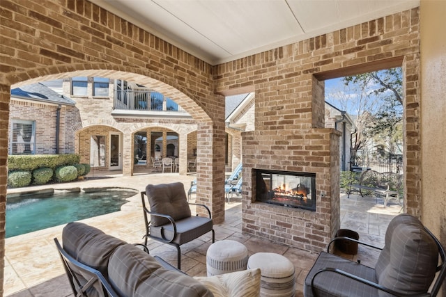 view of patio / terrace with a balcony and an outdoor brick fireplace