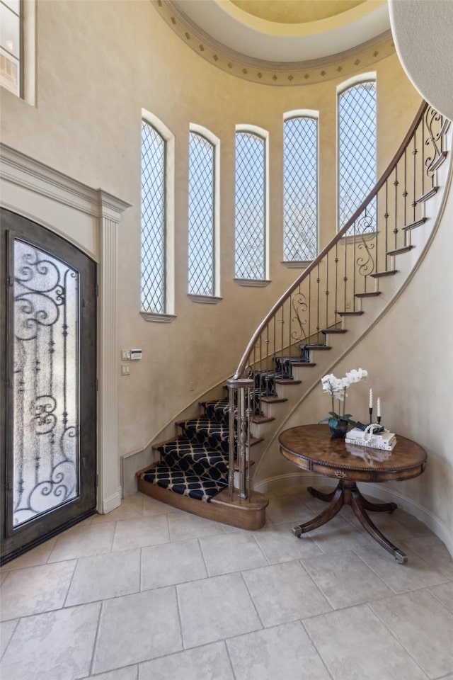 entryway featuring baseboards, stairs, and a high ceiling