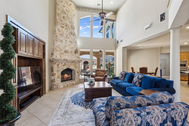 living area with a healthy amount of sunlight, a fireplace, a ceiling fan, and ornate columns