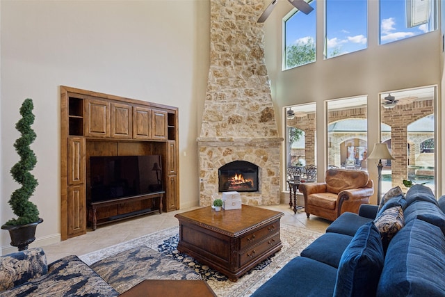 living area with light tile patterned flooring, a fireplace, baseboards, and a ceiling fan