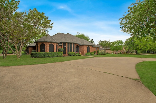 french country style house with a front yard, brick siding, and driveway