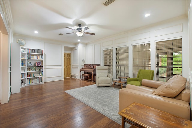 living room featuring visible vents, crown molding, ceiling fan, wood finished floors, and a decorative wall