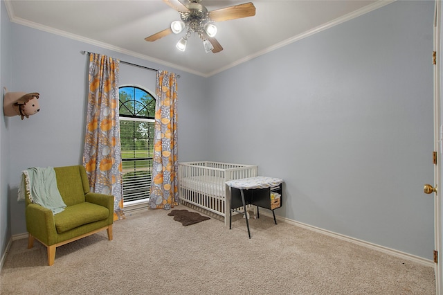 bedroom with a crib, crown molding, carpet flooring, and baseboards