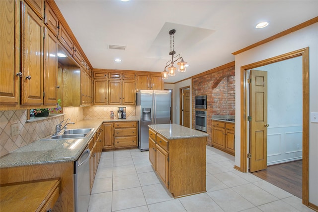 kitchen with a kitchen island, light tile patterned flooring, a sink, ornamental molding, and stainless steel appliances