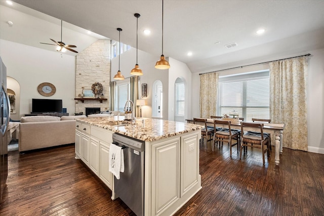 kitchen featuring light stone counters, dark wood finished floors, arched walkways, dishwasher, and open floor plan