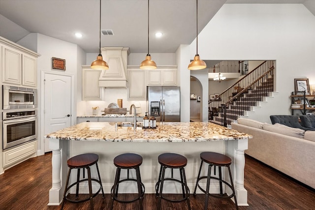 kitchen featuring arched walkways, appliances with stainless steel finishes, dark wood-type flooring, and a kitchen bar