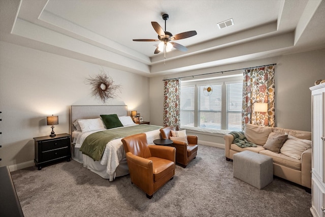 bedroom with visible vents, baseboards, a tray ceiling, carpet flooring, and a ceiling fan