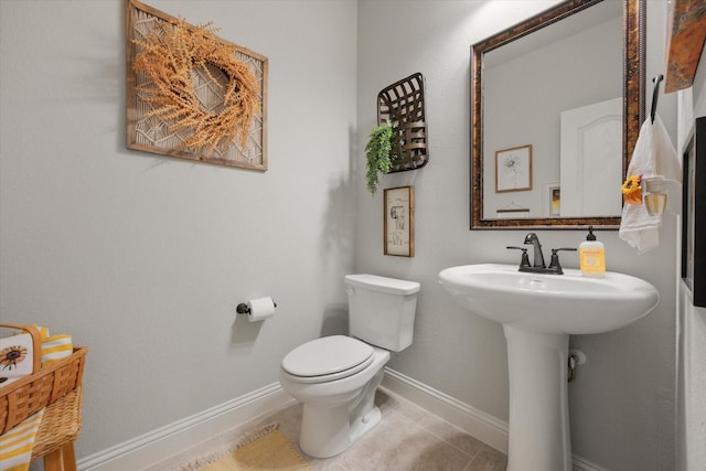 half bathroom featuring tile patterned floors, toilet, and baseboards