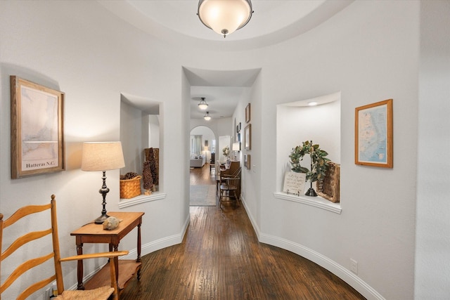 hallway with baseboards, arched walkways, and wood-type flooring