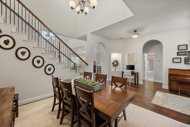 dining area with stairs, light wood-style flooring, baseboards, and arched walkways