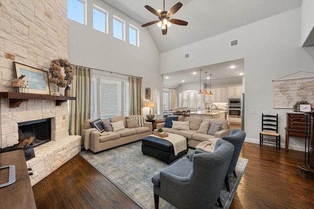 living area featuring visible vents, baseboards, dark wood-type flooring, and a fireplace