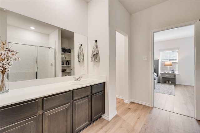 full bath featuring a shower stall, vanity, baseboards, and wood finished floors