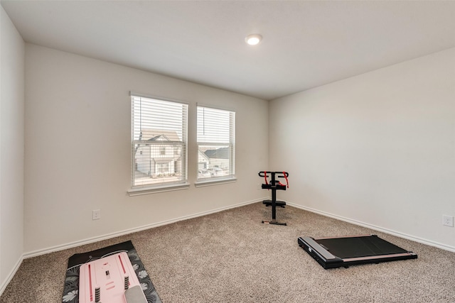 exercise room with baseboards and carpet floors