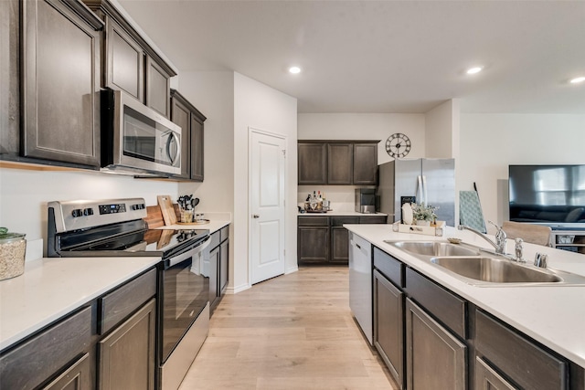 kitchen featuring recessed lighting, a sink, light countertops, appliances with stainless steel finishes, and light wood-type flooring