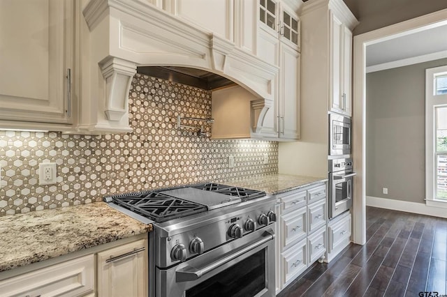 kitchen featuring dark wood-type flooring, light stone counters, backsplash, stainless steel appliances, and baseboards