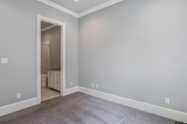 unfurnished bedroom featuring crown molding, ensuite bathroom, baseboards, and carpet floors