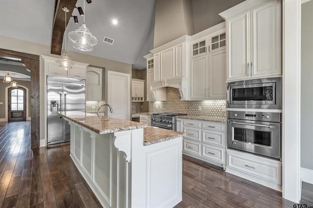 kitchen featuring tasteful backsplash, built in appliances, light stone counters, and visible vents