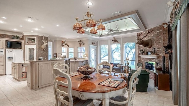 dining area with light tile patterned floors, visible vents, a fireplace, and crown molding