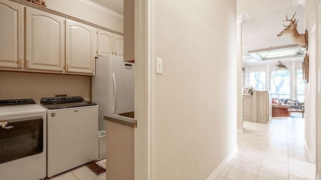 clothes washing area featuring baseboards, light tile patterned flooring, cabinet space, crown molding, and washing machine and dryer