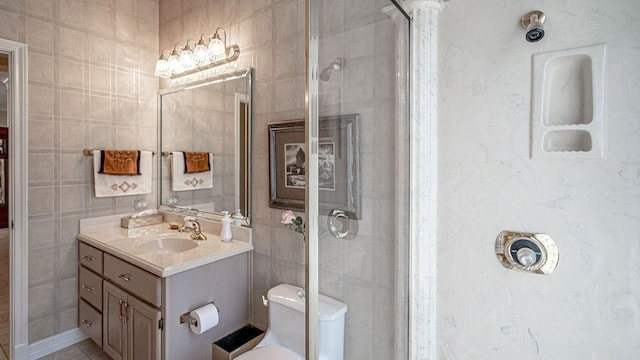 bathroom with a shower stall, tile walls, vanity, and toilet