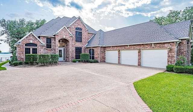 view of front of property with brick siding, roof with shingles, and driveway