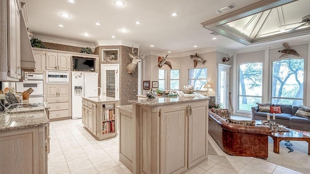 kitchen with visible vents, crown molding, recessed lighting, white fridge with ice dispenser, and a kitchen island with sink