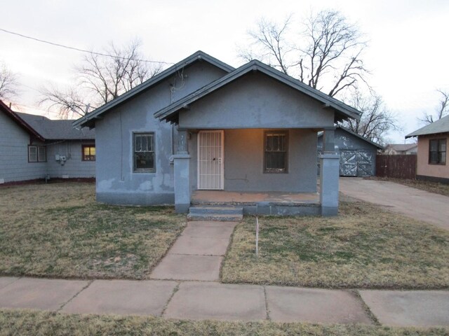 711 N 10th St, Memphis, TX 79245 - bungalow-style home with stucco siding, an outbuilding, covered porch, and a front yard