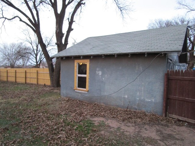 711 N 10th St, Memphis, TX 79245 - view of side of property featuring stucco siding, a shingled roof, and fence