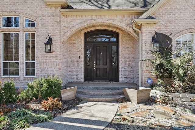 property entrance with brick siding and a shingled roof