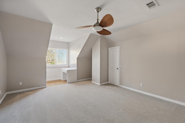 additional living space featuring visible vents, baseboards, light colored carpet, and vaulted ceiling