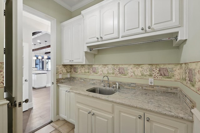 kitchen featuring white cabinetry, light stone counters, backsplash, and a sink