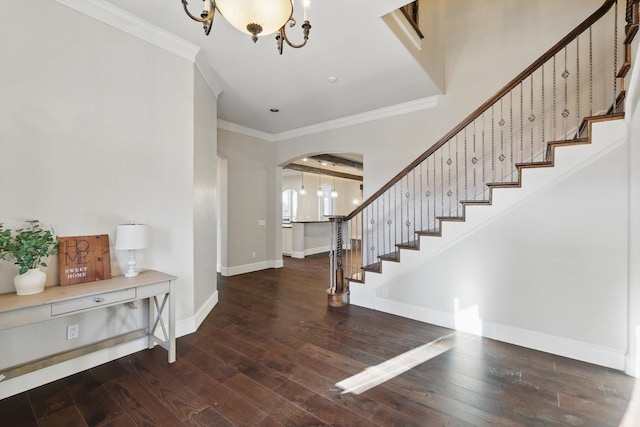 foyer entrance featuring baseboards, stairs, ornamental molding, hardwood / wood-style flooring, and arched walkways