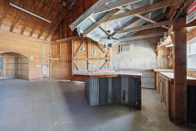 miscellaneous room featuring a wall mounted air conditioner, lofted ceiling, a workshop area, and concrete flooring