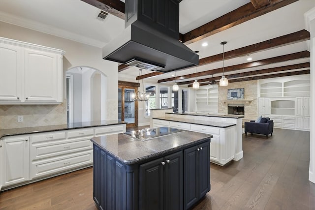 kitchen featuring a fireplace, island exhaust hood, dark wood-style flooring, and a kitchen island