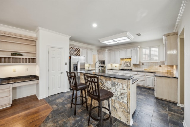 kitchen featuring a kitchen bar, dark countertops, crown molding, decorative backsplash, and built in study area