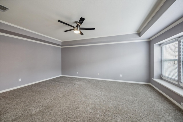 carpeted spare room with a ceiling fan, crown molding, baseboards, and visible vents