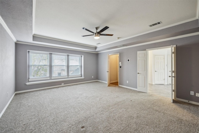 unfurnished room featuring visible vents, baseboards, a tray ceiling, ornamental molding, and carpet flooring