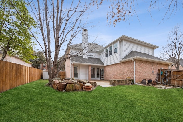 back of house with brick siding, a lawn, a chimney, and a fenced backyard