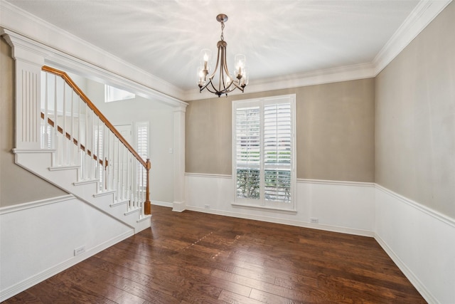 empty room with hardwood / wood-style floors, stairway, ornate columns, crown molding, and a chandelier