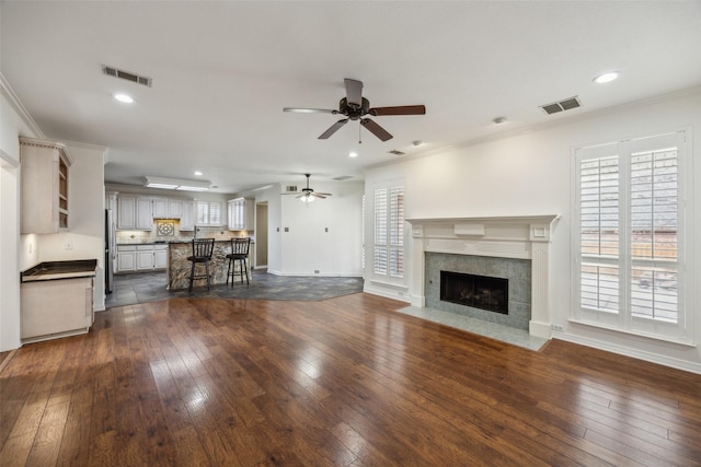 unfurnished living room with dark wood-style floors, visible vents, and ornamental molding