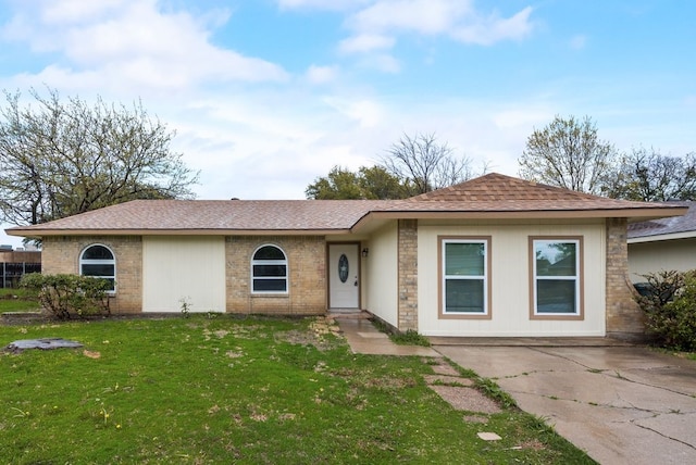 single story home with brick siding, a front lawn, and roof with shingles