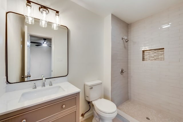 bathroom with tiled shower, toilet, and vanity