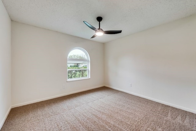 carpeted spare room featuring baseboards, a textured ceiling, and ceiling fan