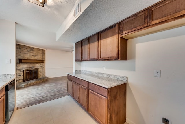 kitchen featuring visible vents, a brick fireplace, open floor plan, dishwashing machine, and a textured ceiling