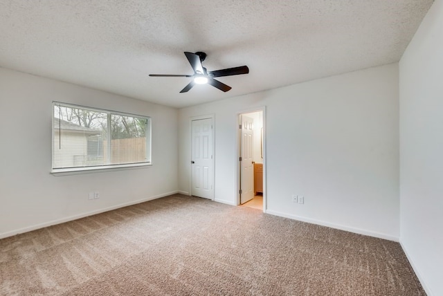 unfurnished bedroom featuring baseboards, light carpet, and a textured ceiling