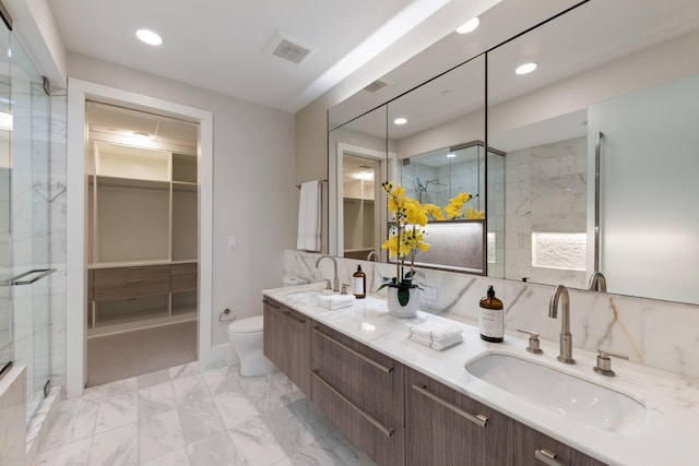 full bath with a sink, double vanity, toilet, and marble finish floor
