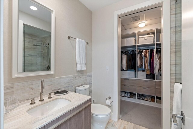 bathroom featuring a spacious closet, visible vents, a shower stall, toilet, and vanity